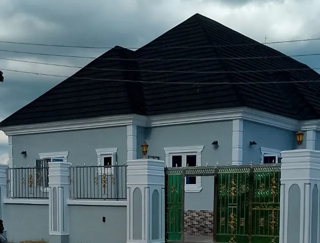 Juls & Riff Delta apartment building with pale blue-grey walls, a dark hip roof and a green and gold gate