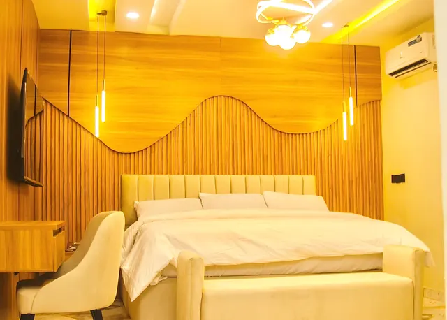 Comfort Room with a wave-shaped wood-slat feature wall, a bed with a cream bench and a desk chair