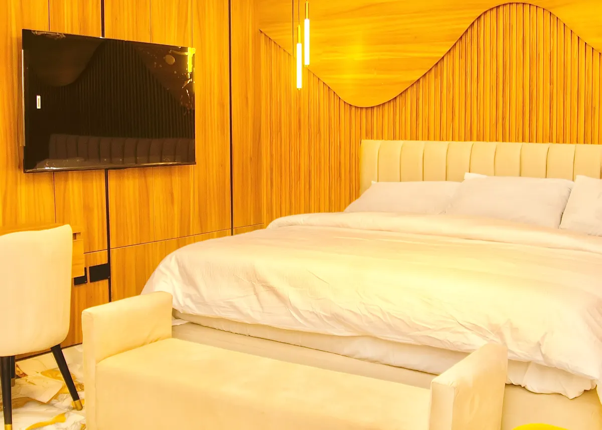 Comfort Room with a wave-shaped wood-slat wall, wall-mounted TV and bed