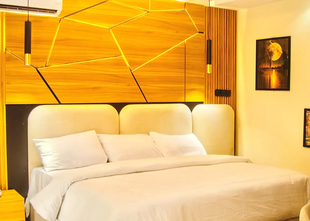 Comfort Room bed with a three-lobe cream headboard beneath a lit geometric wall panel