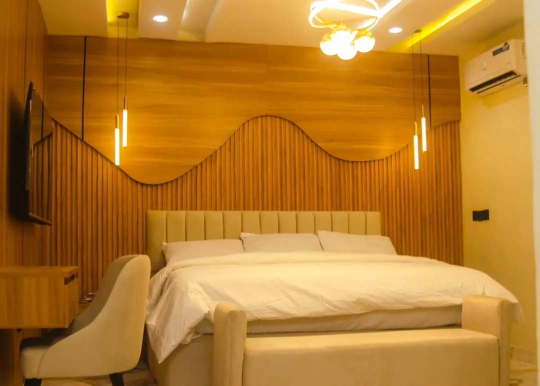 Executive Room bed and bench in front of a wave-shaped wood-slat wall
