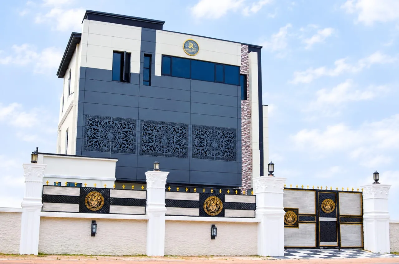 Front of the Juls & Riff Lagos hotel with its decorative gate, ornamental screens and gold J&R emblem under a clear sky