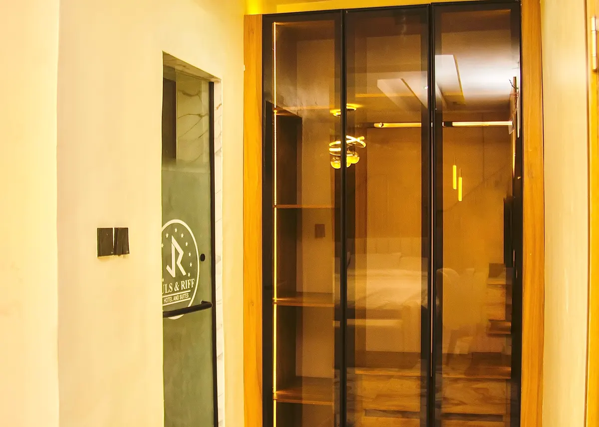 Glass-fronted wardrobe in a guest room beside the bathroom door bearing the Juls & Riff emblem